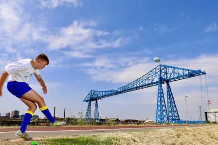 Matty Lynn kicking a ball over the Transporter Bridge | Tees Valley Combined Authority